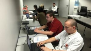 Students working at their desks in a classroom learning computer skills.