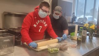 A person learning cooking skills as he's rolling dough.