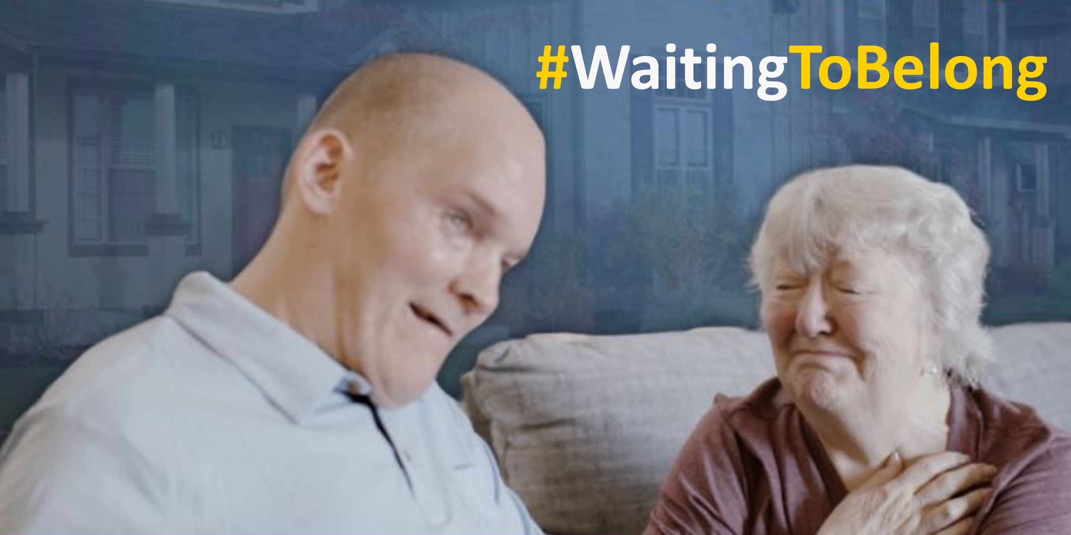 A smiling man and an elderly woman sit close together on a couch. The woman touches her chest, appearing emotional. The words "#WaitingToBelong" are displayed in bold yellow and white text in the corner.